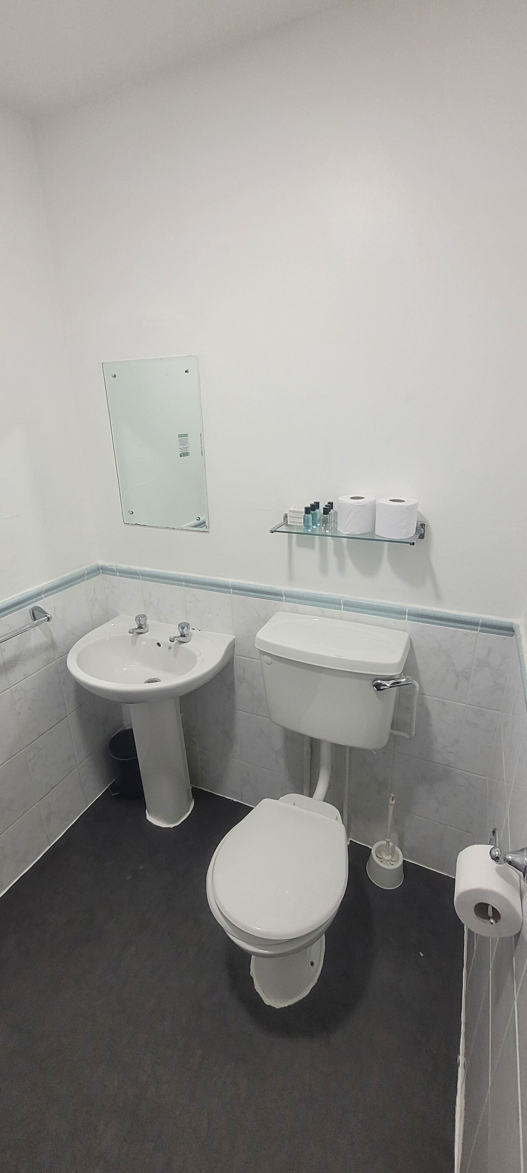 Ein kleines Badezimmer mit Waschbecken, Toilette und Spiegel.