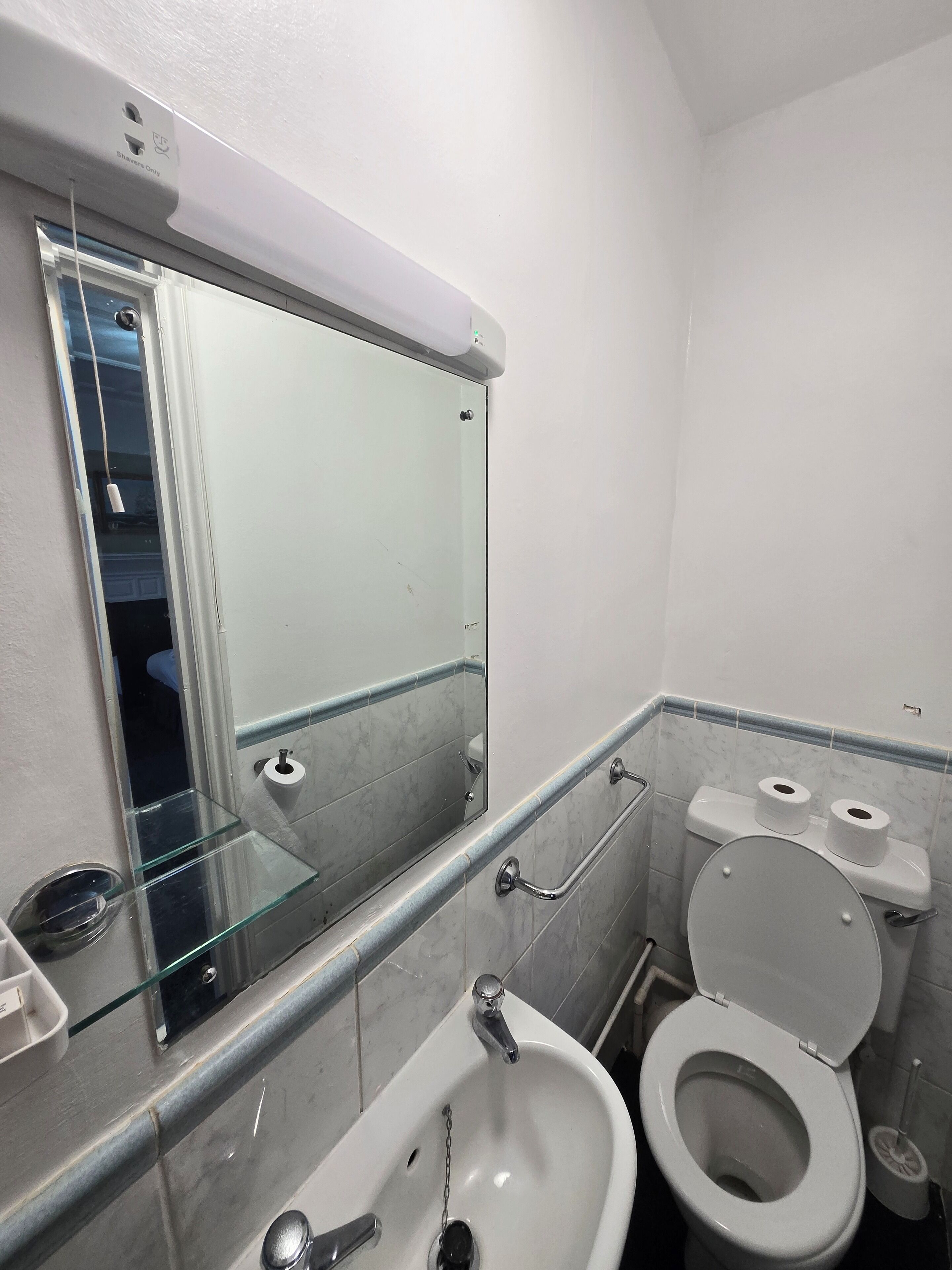 A bathroom with a glass sink, a mirror, a toilet, and a bidet.