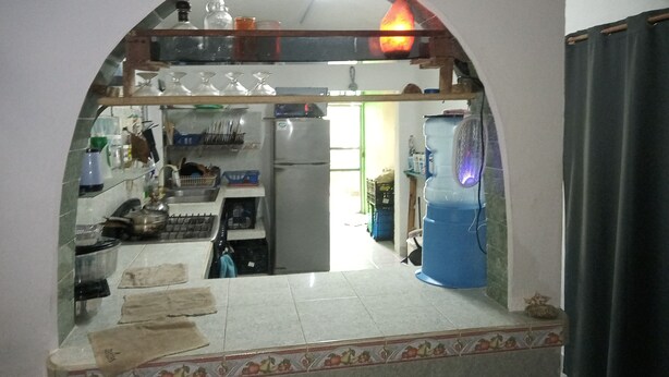 A kitchen with a tiled floor, a refrigerator, a blue water dispenser, and various kitchen utensils and appliances. - Divers Hostel Cozumel (Cozumel)