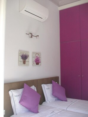 A bedroom with a bed, two purple pillows, a white air conditioner, and a purple wardrobe. - 'Inn Chiado - Double Room 1' with Balcony, Wi-Fi and Air Conditioning (Lisboa)