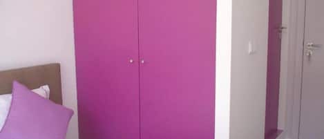 Ein Schlafzimmer mit einem Bett, einem violetten Kleiderschrank und einer Tür.
