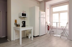 A kitchenette with a microwave, refrigerator, coffee maker, and a small table with chairs. - 'Inn Chiado - Double Room 1' with Balcony, Wi-Fi and Air Conditioning (Lisboa)