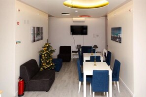 Una sala de estar moderna con un televisor de pantalla plana, un árbol de Navidad, un sofá, una mesa de comedor con sillas y un extintor.