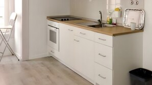 A modern kitchen with white cabinets, a wooden countertop, and a black trash bin. - 'Inn Chiado - Double Room 6' with Balcony, Wi-Fi and Air Conditioning (Lisboa)