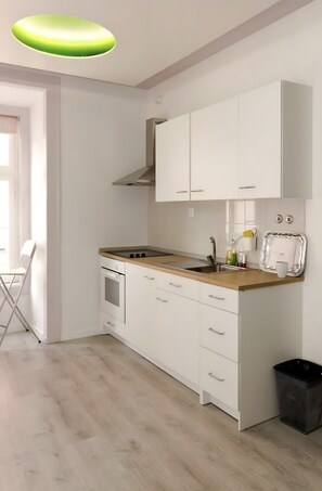 A modern kitchen with white cabinets, a wooden countertop, and a black trash bin. - 'Inn Chiado - Double Room 6' with Balcony, Wi-Fi and Air Conditioning (Lisboa)