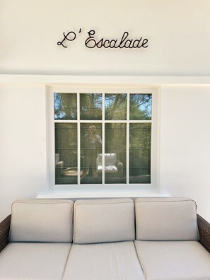 A room with a large window, a sofa, and a wall-mounted sign reading 'L'Escalade'. - Renovated house in top Cap Ferret location A0344 (Lège-Cap-Ferret)