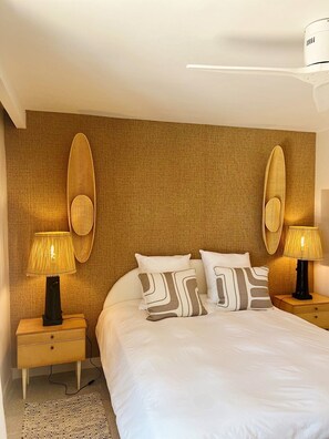 A hotel room with a large bed, two nightstands with lamps, a textured wall, and a ceiling-mounted air conditioning unit. - Renovated house in top Cap Ferret location A0344 (Lège-Cap-Ferret)