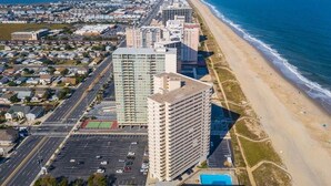 An aerial view of a coastal city with high-rise buildings, a beach, and a parking lot. - Oceanfront 15th Floor Condo w/ Balcony & Pool (Ocean City)