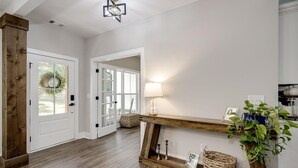 Ein geräumiger Korridor mit Holzboden, weißen Wänden und einem Holzkonsole mit Lampe und Dekoration.