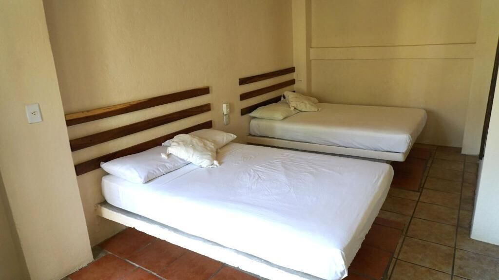 A room with two beds, each with wooden headboards and white bedding.