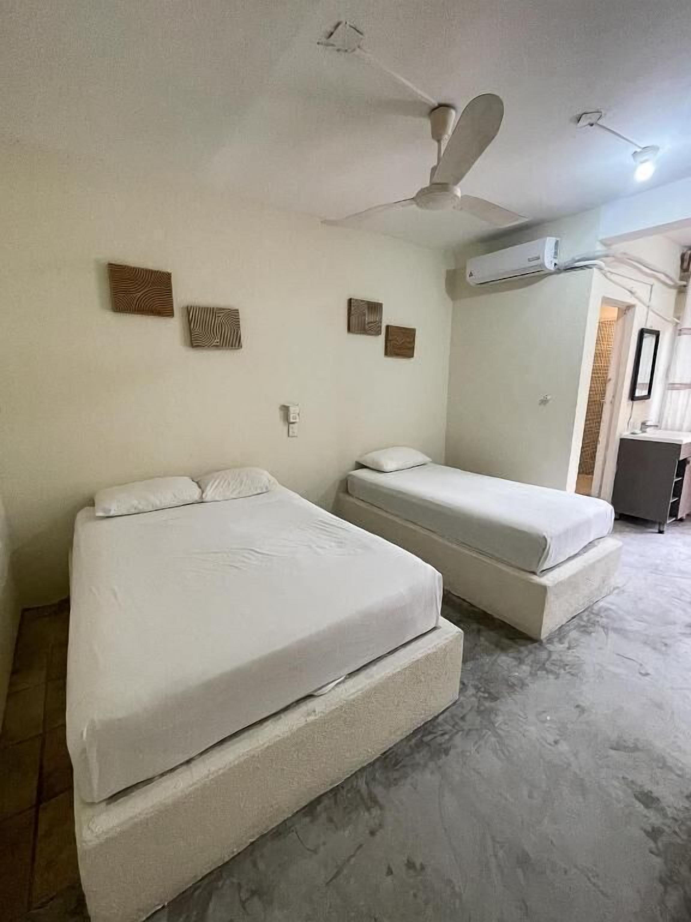 A room with two beds, a ceiling fan, and an air conditioning unit.
