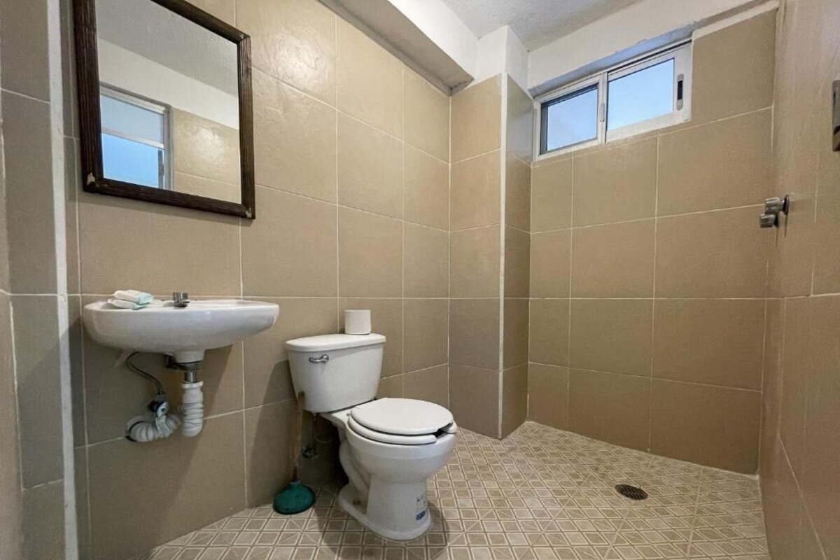 A bathroom with a toilet, sink, and mirror.