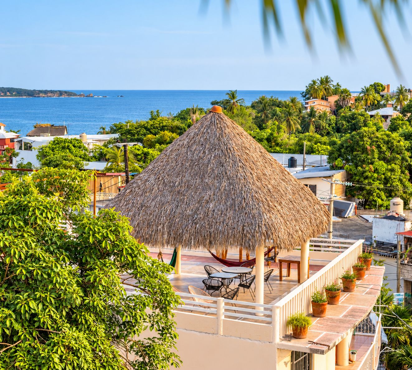 Gazebo con tetto di paglia e posti a sedere esterni, immerso nel verde e con vista sulla costa.
