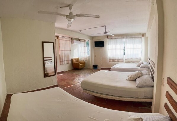 A room with two beds, a ceiling fan, a TV, and a chair. - Casa Laani (San Pedro Mixtepec)