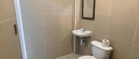 A small bathroom with a toilet, sink, and mirror.