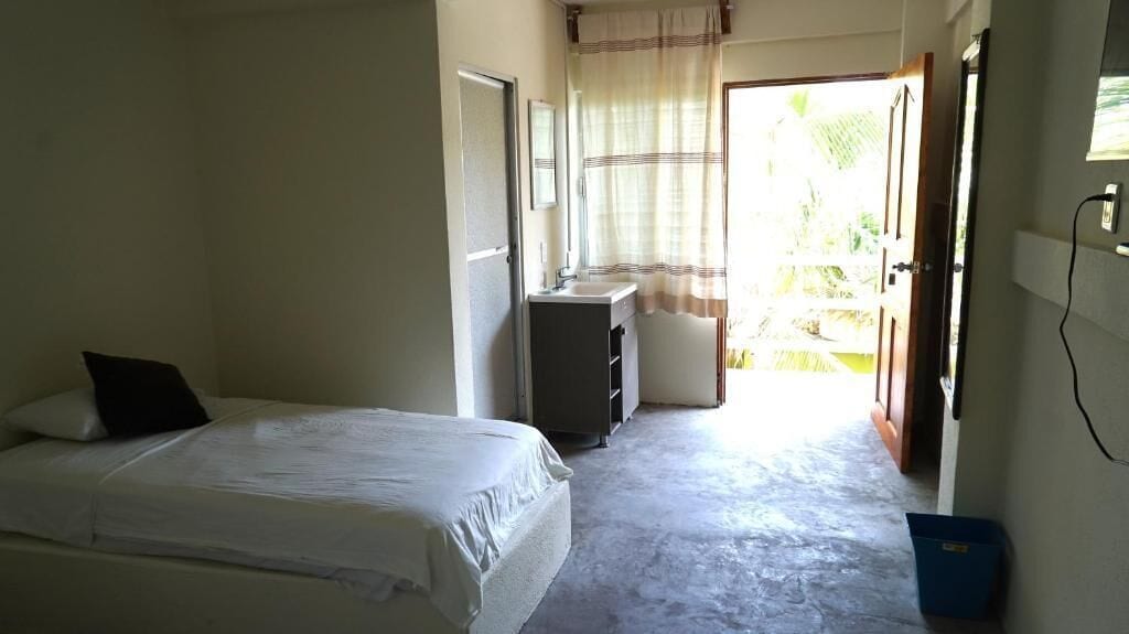 A bedroom with a bed, a small desk, and a window with curtains.