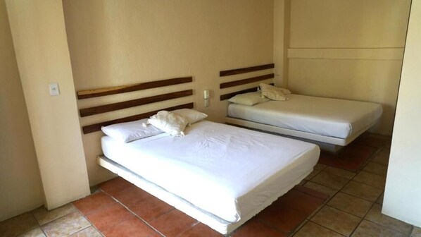 A room with two beds, each with wooden headboards and white bedding. - Casa Laani (San Pedro Mixtepec)