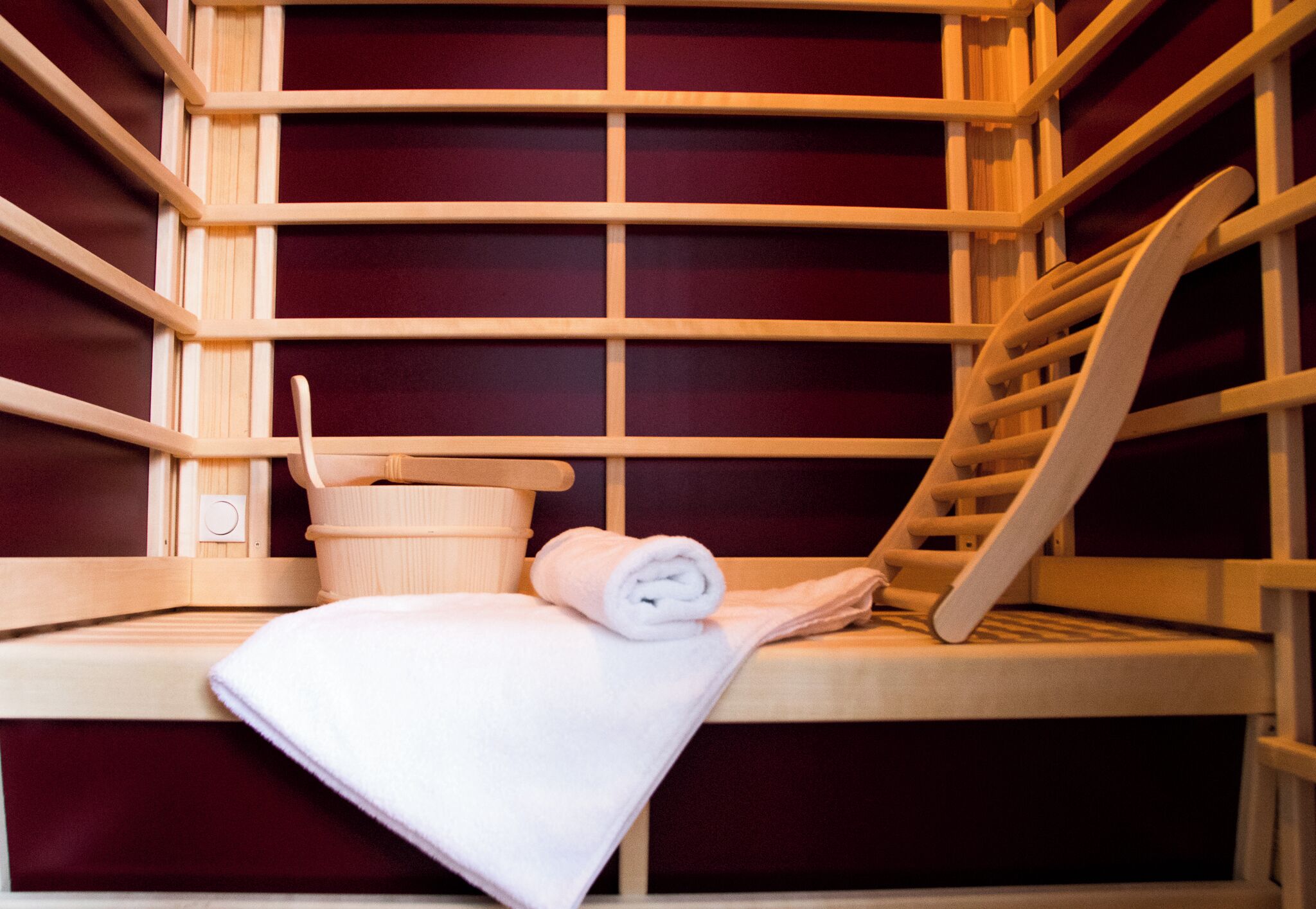 En sauna med træbænke, et håndklæde og en træspand.
