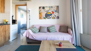 Un salon moderne avec un canapé rose, une table basse en bois et un tableau abstrait aux couleurs vives accroché au mur.