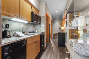 A compact kitchen with wooden cabinets, a built-in dishwasher, a toaster, and a kettle. - Condo in River Run Village! Fireplace! 5 Minute Walk to the Ski Lift! (Keystone)