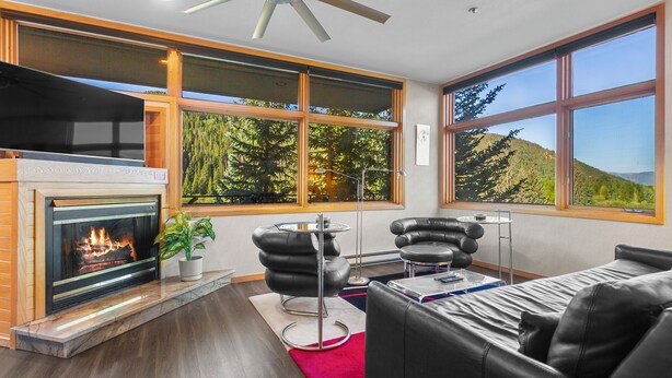 Ein modernes Wohnzimmer mit Kamin, Ledermöbeln und großen Fenstern mit Blick auf einen Wald.