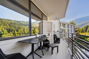 A balcony with a table and chairs, overlooking a forested valley and a mountain. - Condo in River Run Village! Fireplace! 5 Minute Walk to the Ski Lift! (Keystone)