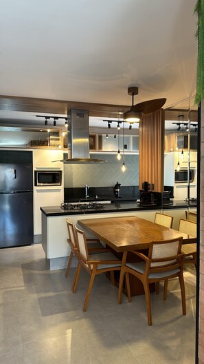Una cocina moderna con una isla central, electrodomésticos integrados e iluminación colgante.
