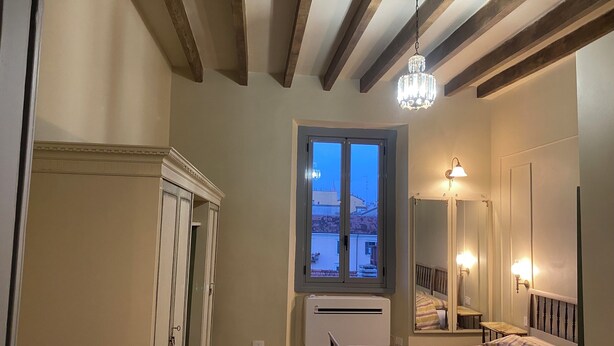 Un dormitorio con cama, armario, ventana con vistas y candelabro.