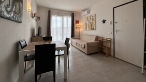 A modern living room with a dining area, a sofa, a TV, and artwork on the walls. - Sea View Residence with Pool (Lu Bagnu)