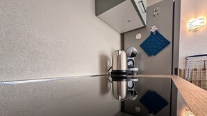 A modern bathroom with a reflective floor, a towel rack with a blue towel, and a wall-mounted light fixture. - Sea View Residence with Pool (Lu Bagnu)