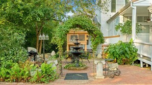 Un giardino con una fontana, un gazebo e un vialetto in mattoni.