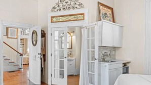 Un ambiente compatto con angolo cottura, zona pranzo e una scala che conduce a un'altra stanza.