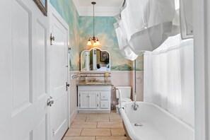 A bathroom with a white bathtub, a vanity with a mirror, and a shower curtain.