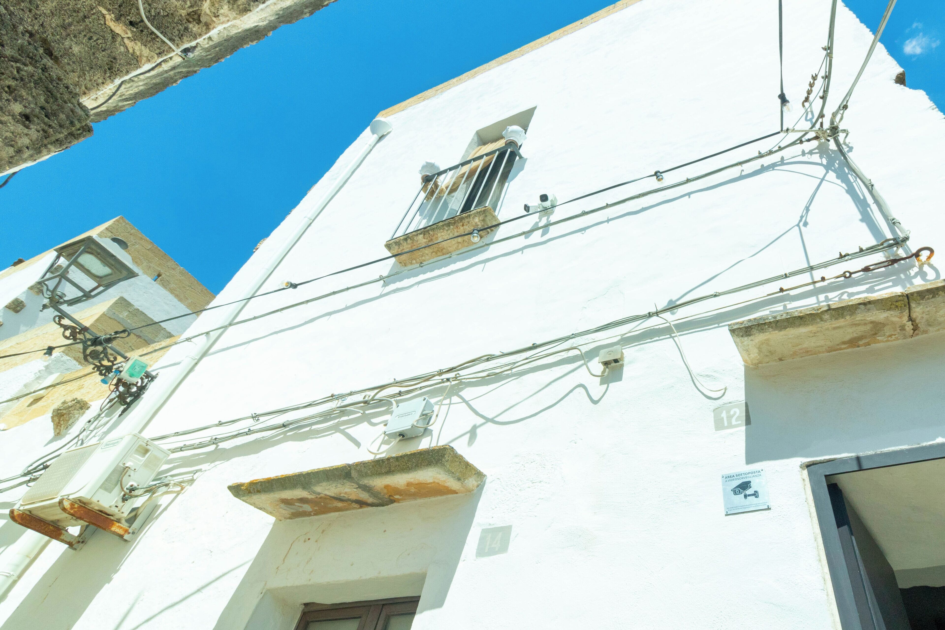 A white building with multiple balconies and visible electrical wiring.