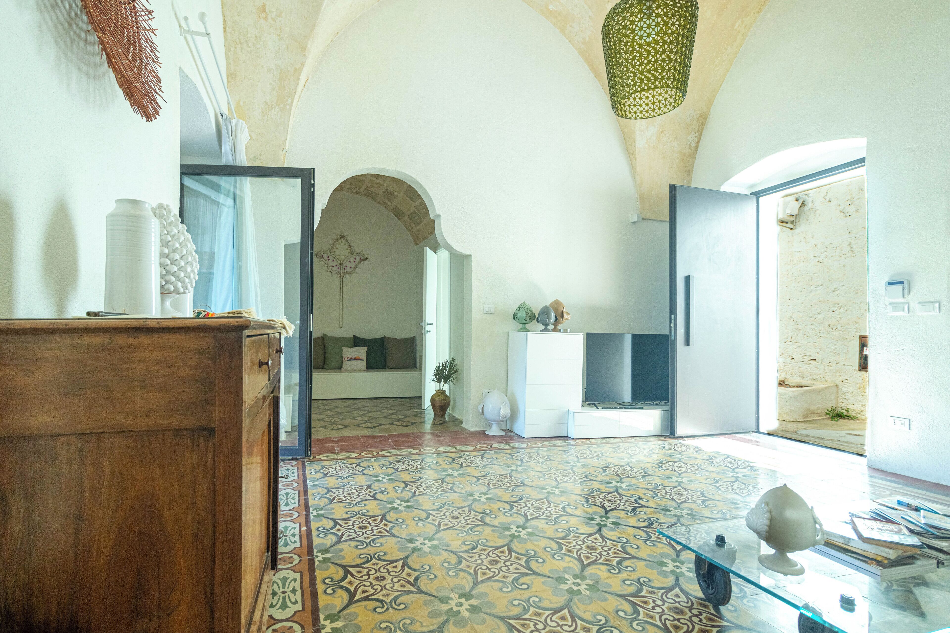 Una habitación amplia con suelo estampado, un armario de madera y una mesa de cristal con adornos.