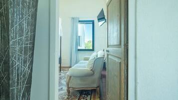 A hallway with a patterned floor, a white sofa, and a window with curtains.
