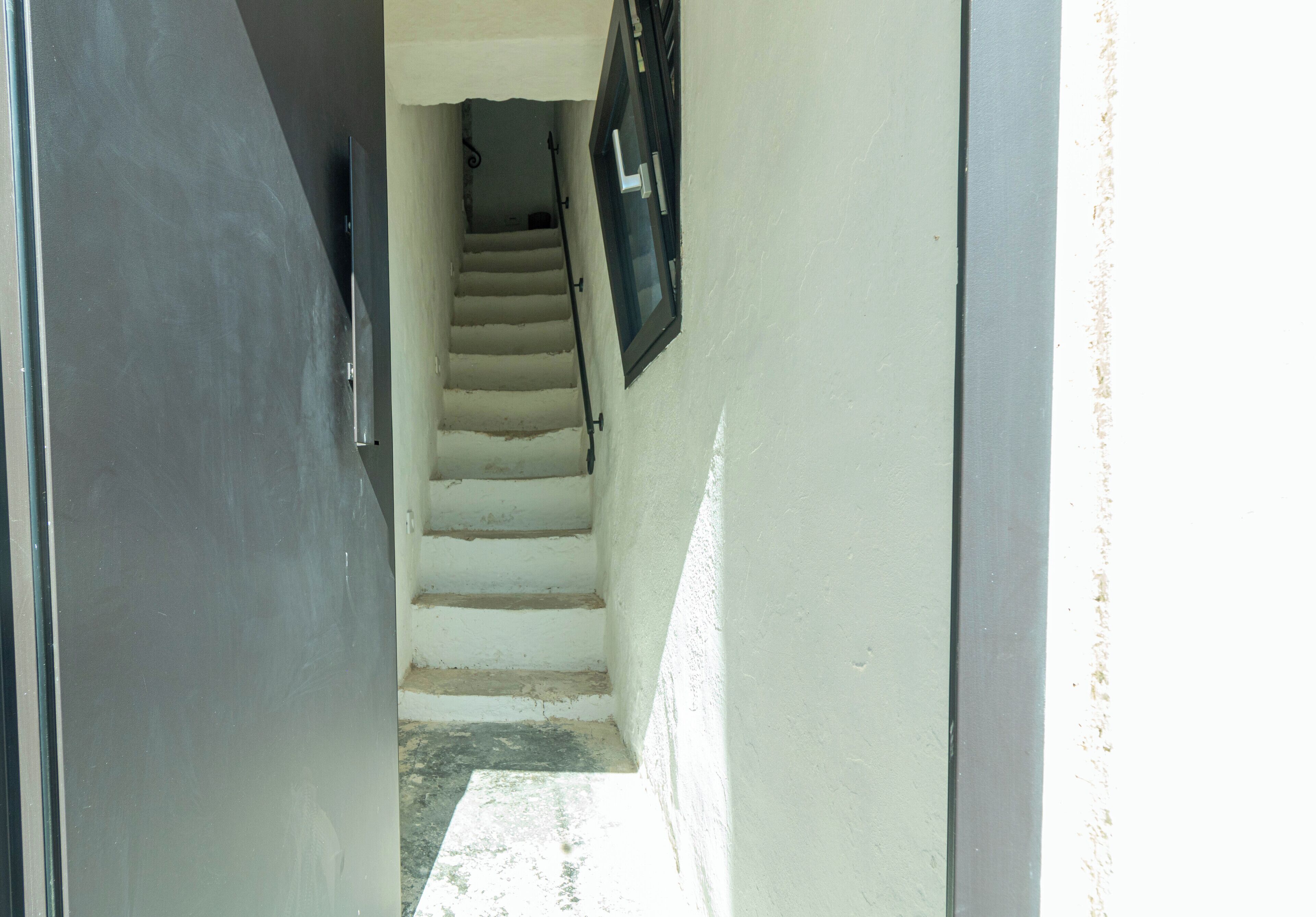 Un escalier étroit menant à un palier sur lequel se trouve une porte en haut.