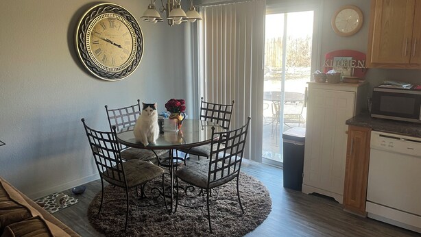 A dining area with a round table, chairs, a clock, and a kitchen in the background. - Adorable townhome with in Blue Springs 10 Miles from GEHA STADIUM (Blue Springs)