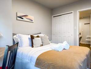 A hotel room with a bed, a chair, a desk, a coat rack, and a door. - Private Studio Near Upenn & Drexel (Philadelphia)