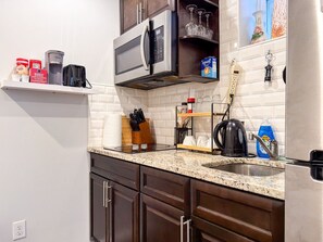 Una cocina equipada con microondas, cafetera y diversos utensilios.