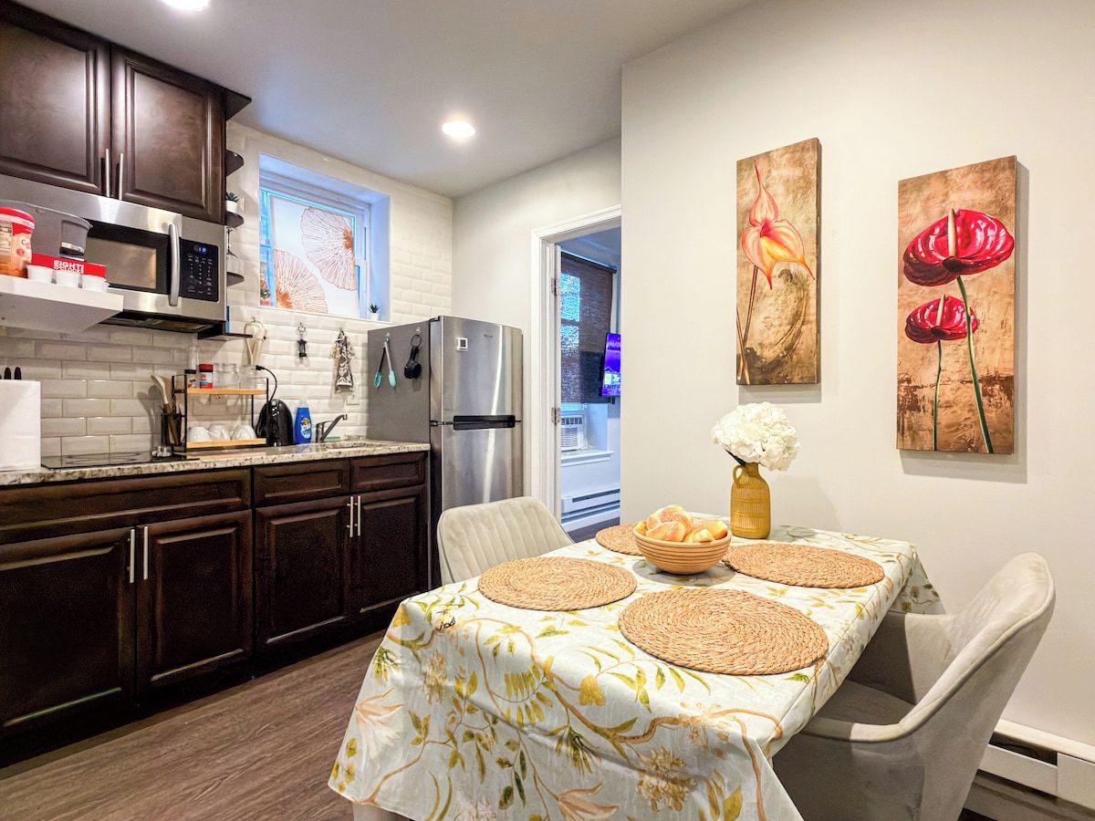 A modern kitchen with dark cabinets, stainless steel appliances, and a dining area with a table set for two.