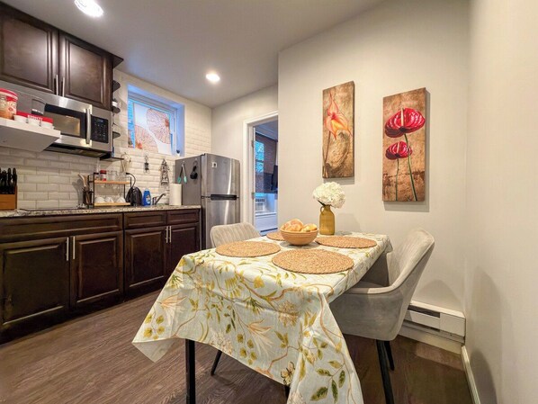 A modern kitchen with dark wood cabinets, stainless steel appliances, and a dining area with a table set for two.