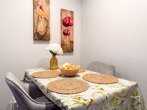 A dining table with placemats, a bowl of fruit, and a vase of flowers.