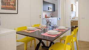 A dining area with a table set for six, yellow chairs, and a framed picture on the wall. - Rome Urban Retreat - ChiacchioProperty (Rome)