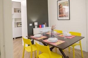 Ein Essbereich mit einem Tisch für vier Personen, gelben Stühlen und einem gerahmten Bild an der Wand.