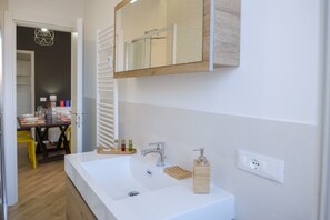 Ein modernes Badezimmer mit einem großen, weißen Waschbecken, einem Spiegel und einem hölzernen Medikamentenschrank.