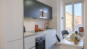 A modern kitchen with white cabinets, a built-in oven, and a window with a city view. - Rome Urban Retreat - ChiacchioProperty (Rome)
