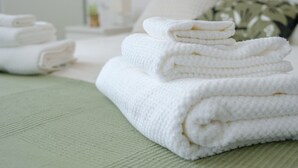 A stack of white towels on a green textured surface, likely in a hotel room. - Rome Urban Retreat - ChiacchioProperty (Rome)