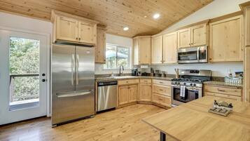 A modern kitchen with wooden cabinets, stainless steel appliances, and a large window.