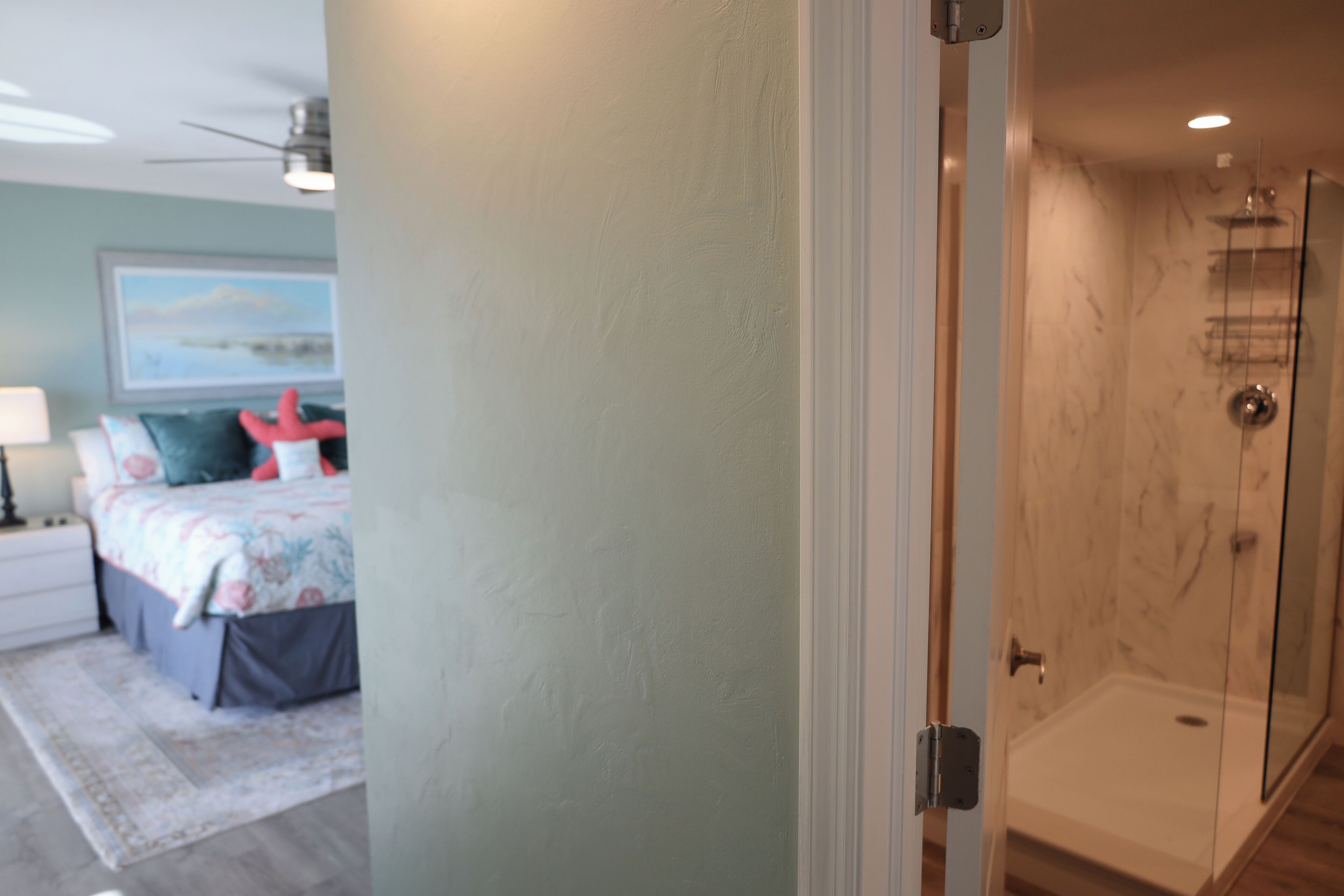 A bedroom with a bed, nightstand, and a wall with a painting.